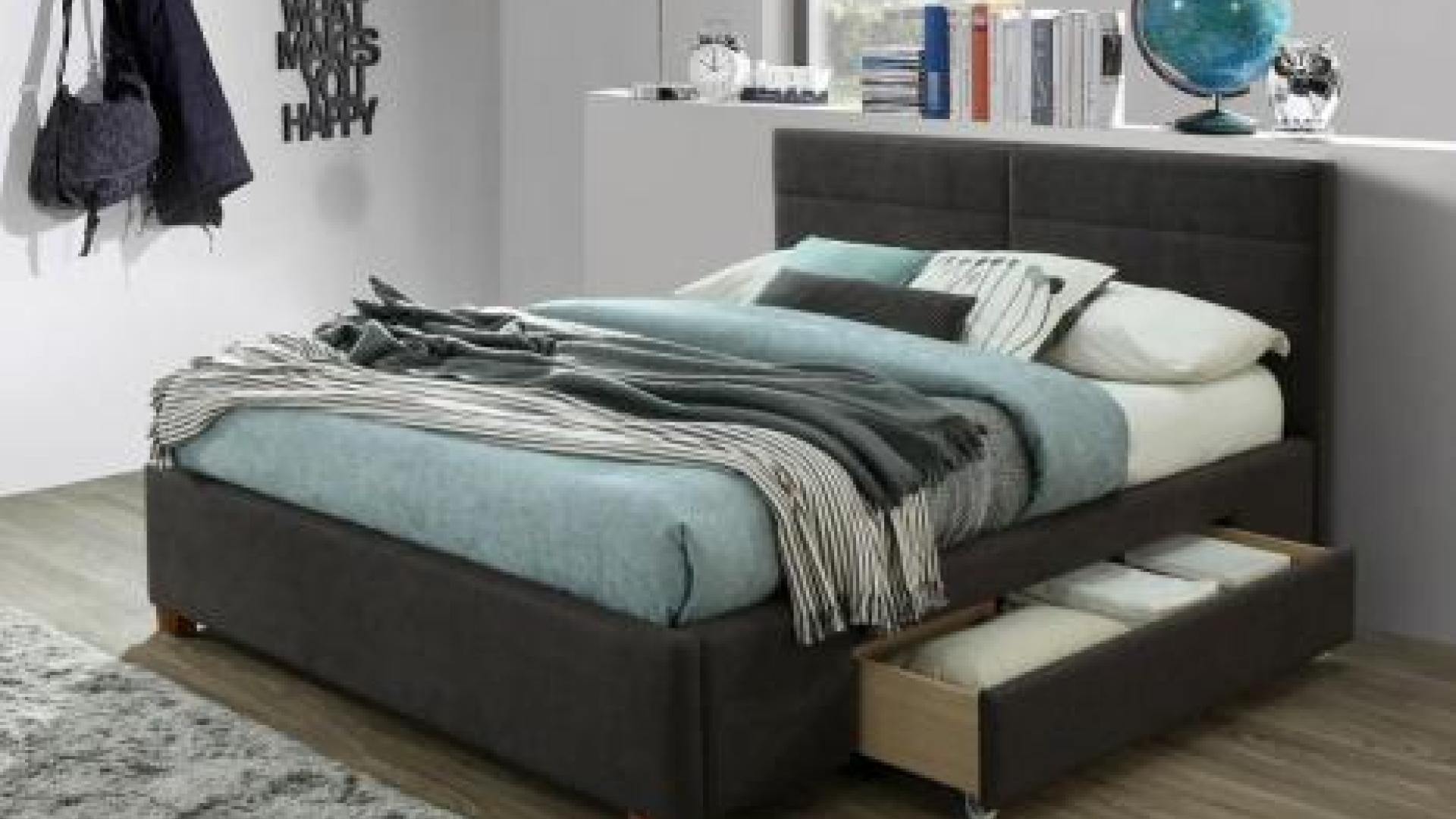 Decorated bedroom with large bed, night table, shelves and wall hangers with purses and jackets/coats hanging from them. The bed has drawers under it.