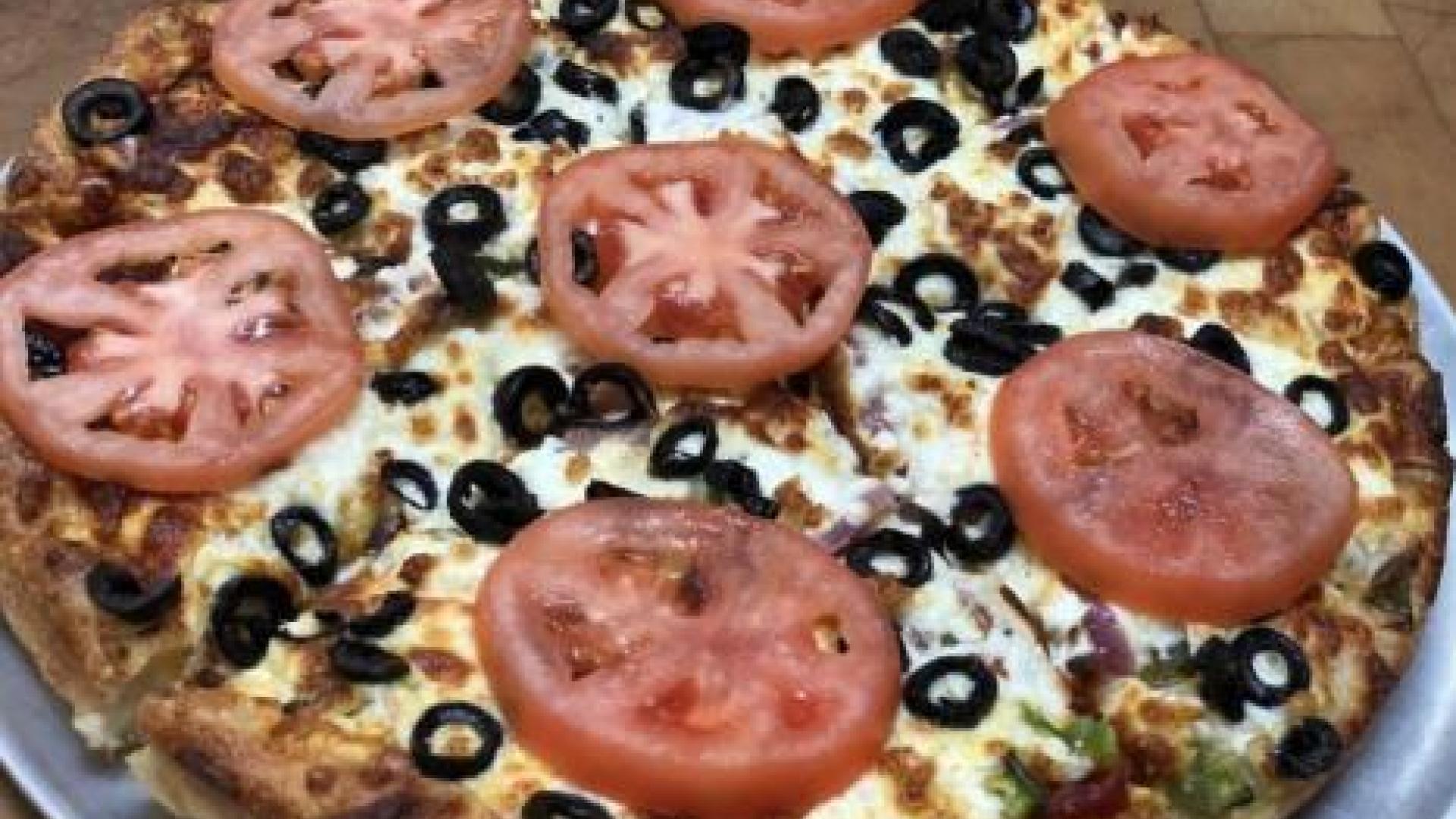 Pizza with sliced tomatoes and olives.