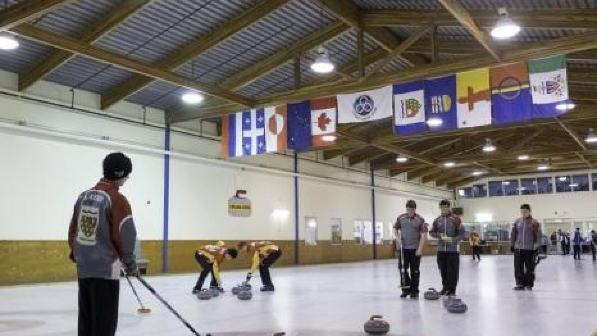 Curling teams playing curling at arena.