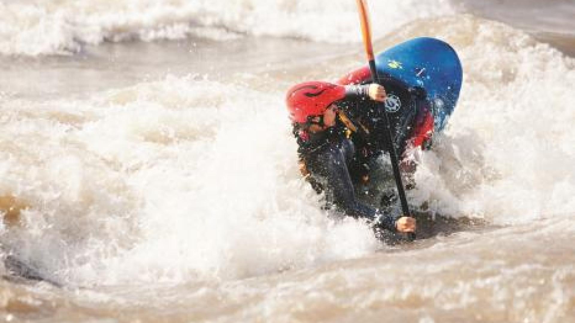 Person kayaking through rough waters.