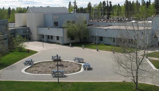 Exterior of Thebacha campus. There are picnic tables surrounding a patch of dirt.