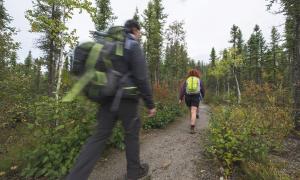 Two people hiking on a trail with trees