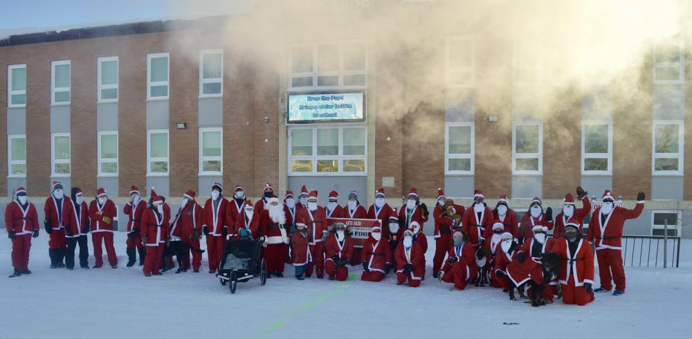 group of santa's in front of a school